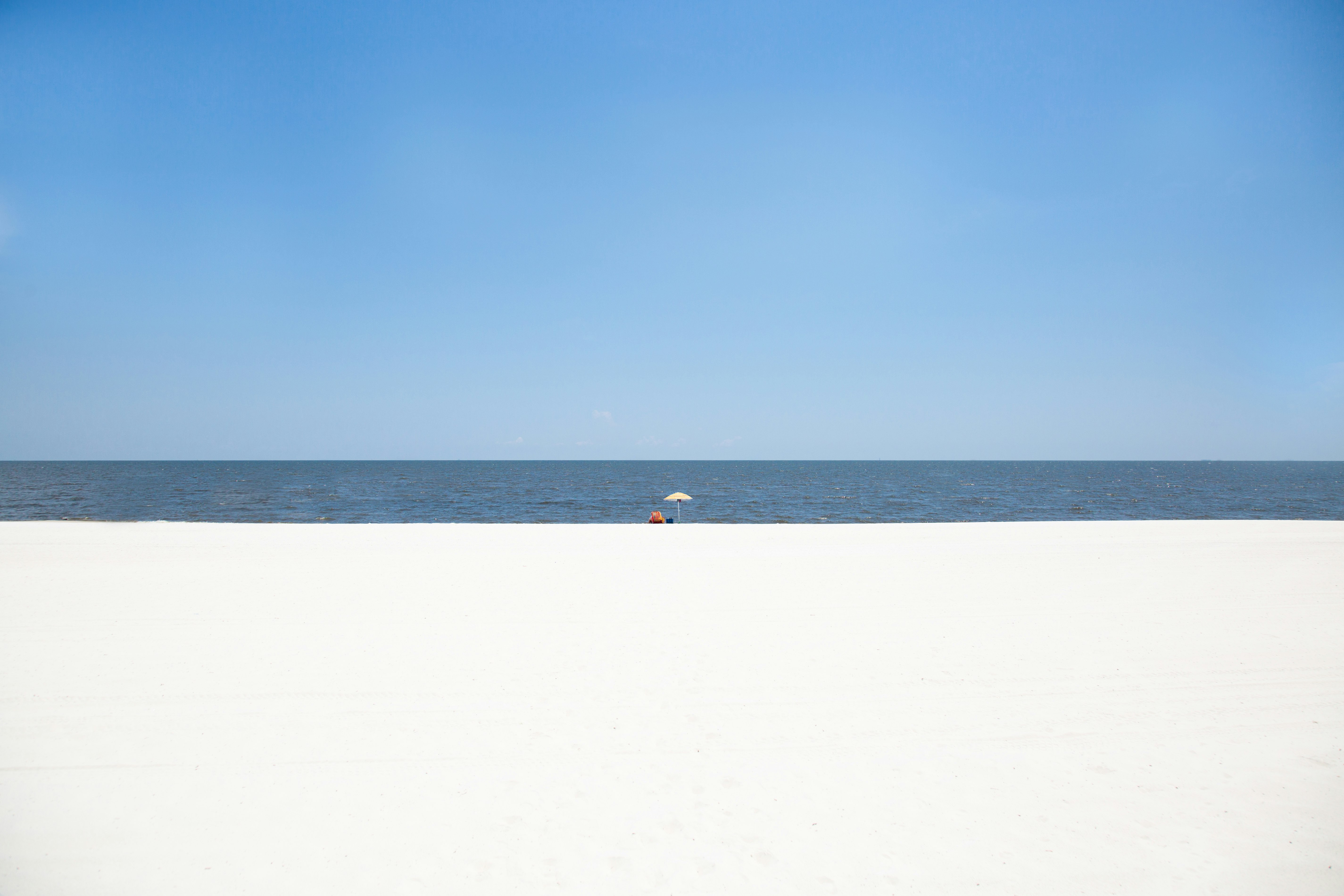 person walking on white sand beach during daytime